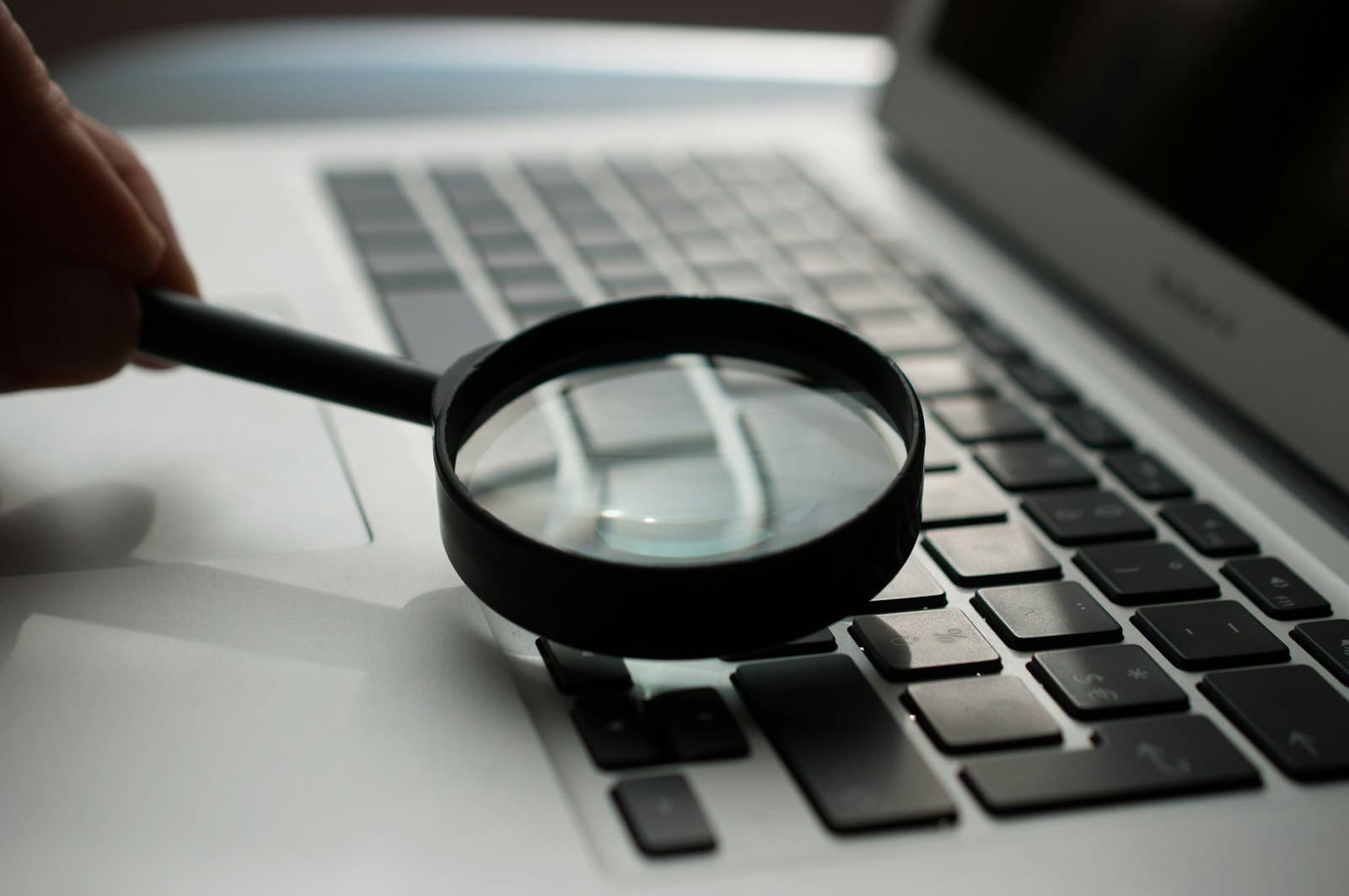 Lupa sobre el teclado de un portátil: metáfora de auditoría y diagnóstico técnico de una web