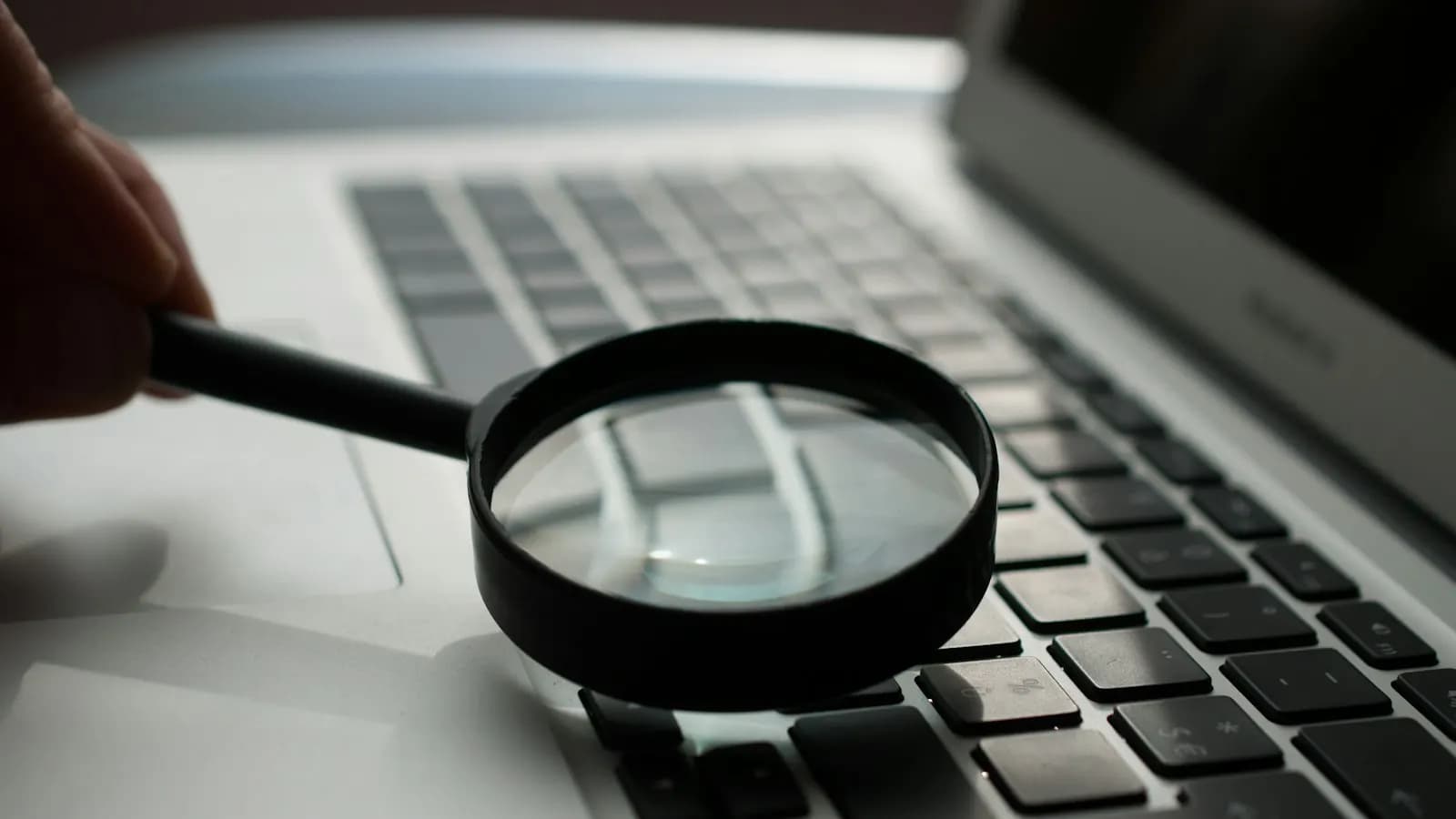 Lupa sobre el teclado de un portátil: metáfora de auditoría y diagnóstico técnico de una web